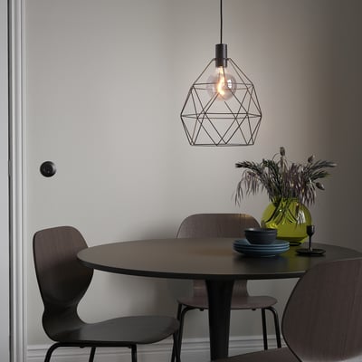 Modern dining area with BRUNSTA black pendant lamp illuminating dark wood table and chairs.