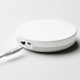Round white DIRIGERA hub with two usb ports and a cable, centralising smart home controls.