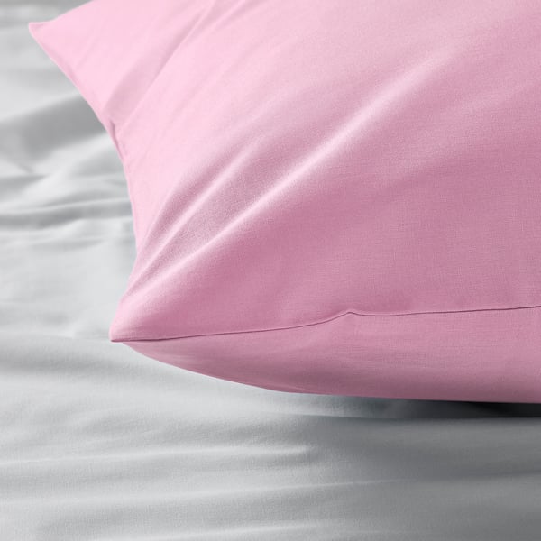 A pink pillowcase on white sheets. Soft, natural cotton fabric is evident.