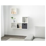 Minimalist wall-mounted shelves, both open and closed, hold books, plants, and decor, offering storage and displaying items neatly.