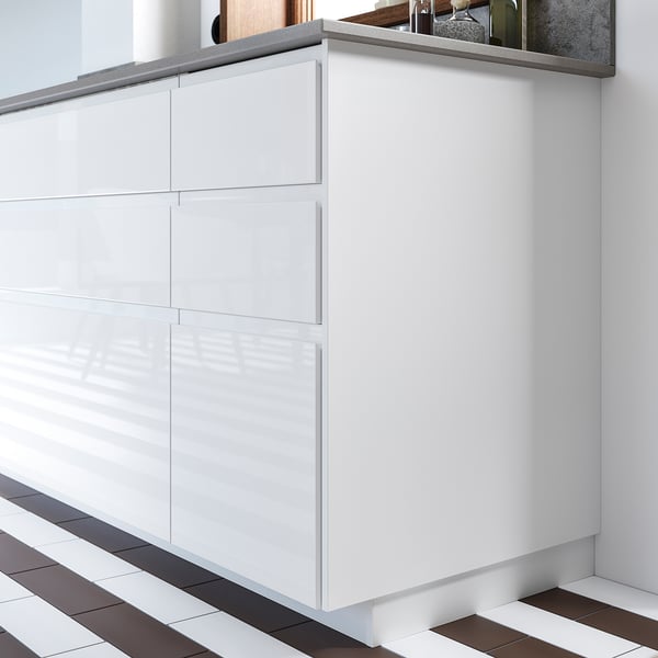 White modern kitchen cabinet with glossy surface. Multiple drawers, sleek design.