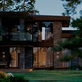 Modern house with GETKÅL string lights, vibrant colours reflecting on dark façade and greenery.