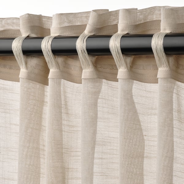 Curtain panel with heading tape and hooks, hanging on a black rod, creating pleated folds.