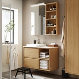 Wooden cabinet under bathroom mirror, open shelves with towels, cohesive wooden design.