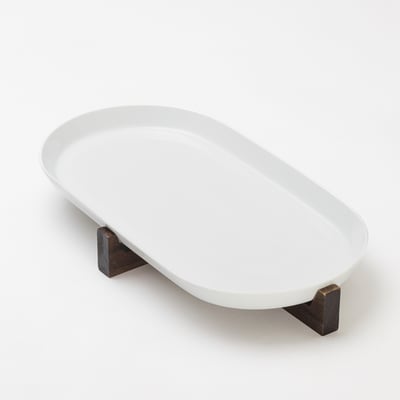 An IKEA 365+ white oval ceramic dish on a dark acacia wood stand. The dish is elevated, perfect for serving.