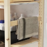 Wooden storage unit with adjustable shelves, holding cleaning bottles and hanging cloth.