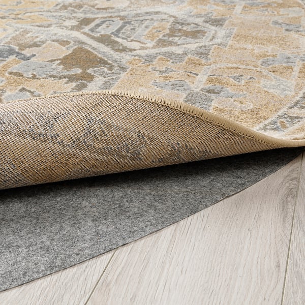 Rug with soft colours folded on stylish wooden floor showing durable backing.