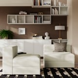 Modern living room with JÄTTEBO sofa, art, rug, books, & lamp, creating cosy, elegant ambiance.