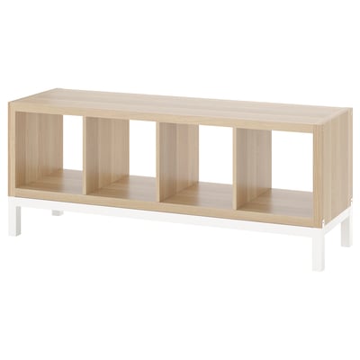 A KALLAX light wood shelving unit with white metal legs. It four open storage sections.