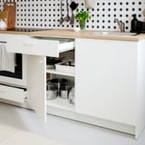 Modern kitchen with white cabinets, oak countertop, stainless steel pots, and a backsplash with black polka dots.