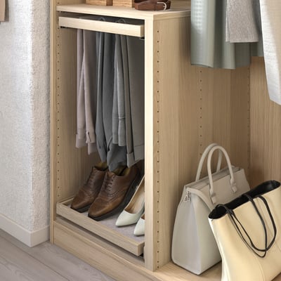 This image shows a well-organized wooden closet with hanging pants, shoes, and handbags.