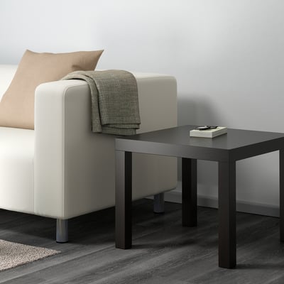 BLACK coffee table next to white sofa with grey blanket & book. Sleek, modern, medium size.