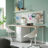 Modern home office with LAGKAPTEN desk, storage, green wall, art supplies, and lamp.