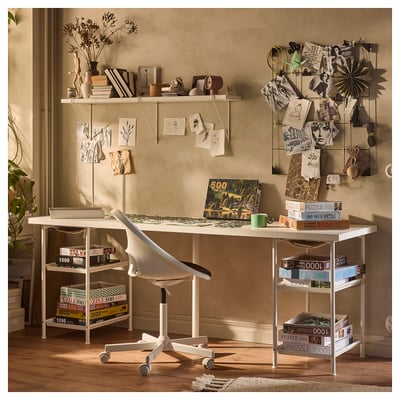 Home office setup with white LAGKAPTEN desk, jigsaw puzzles, chair, wall shelves with decor, and magnetic board.