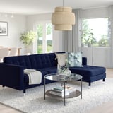 Cosy living room with deep blue l-shaped LANDSKRONA sofa, glass coffee table, and large window.