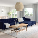 Modern living room with navy sectional, coffee table, window, and light fixture. Bright & cosy.