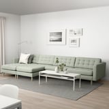 Living room with green l-sofa, photos, coffee table, lamp, rug, wood floor.