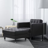 Modern living room setup: black leather armchair & ottoman, minimalist design, lamp & plant on side.