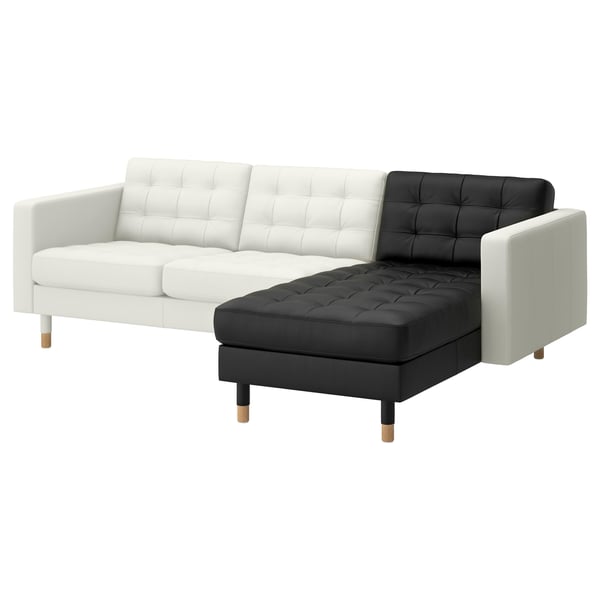 A modern, l-shaped sofa, the LANDSKRONA, with a bicolor scheme of white and black leather. It has tufted cushions and wooden legs.