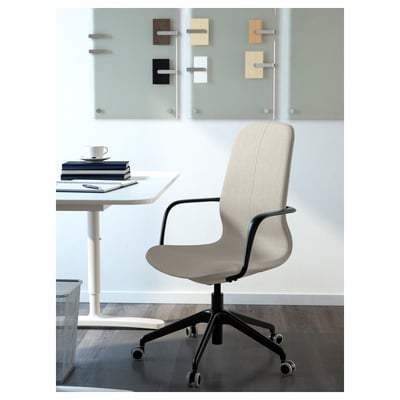 Office setup with a modern, beige LÅNGFJÄLL chair featuring adjustable height and tilt, positioned near a white table holding books and a coffee cup.