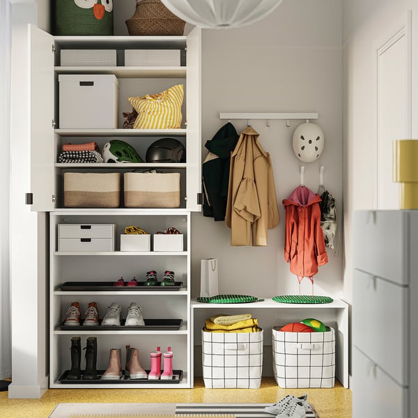 Well-organized closet with shelves and storage bins. Coats hang near helmets. Shoes neatly arranged.