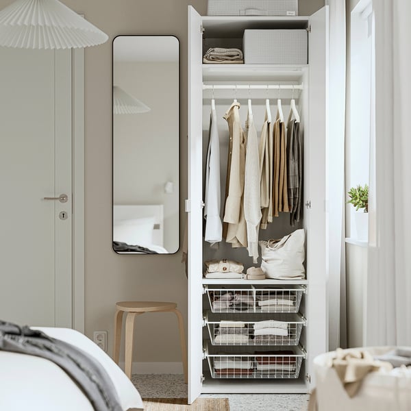 Open closet displaying neatly hung clothes and organised drawers in tidy bedroom.