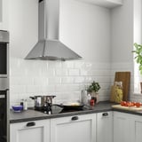 Modern kitchen a large stainless steel range hood with sleek edges and led lighting. White cabinetry and subway tiles complement the stylish design.