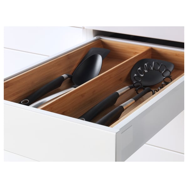 Open kitchen drawer displaying cooking utensils in white cabinet.