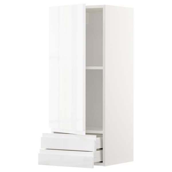 Depicts a white METOD kitchen cabinet with sleek, modern design featuring high gloss finish, integrated handles, and a central drawer.
