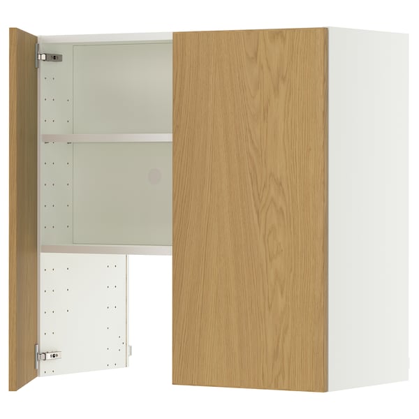 A METOD wall cabinet in oak. Its a square-shaped unit with a wooden door on one side and metal hinges. The interior has two adjustable shelves.