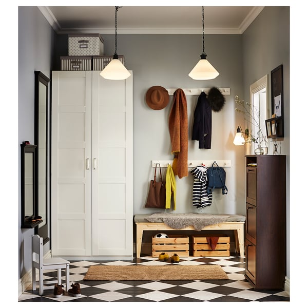 Modern entryway with white PAX wardrobe, black & white chequered floor, hanging clothes & hats, wooden bench, and pendant lights.