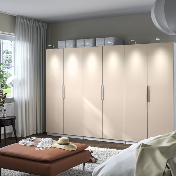 Beige PAX wardrobe with boxes, window, table plant, and bench with clothes and hat.