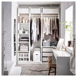 Modern minimalist walk-in closet with clothes, shelves, plants, and vanity area.