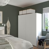 Modern bedroom with dark green walls and white PLATSA wardrobe.