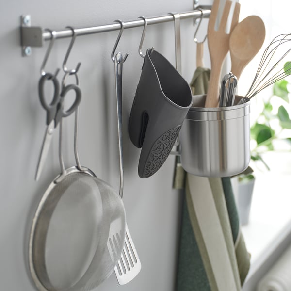 Kitchen hooks holding tools: sieve, spatula, oven mitt, scissors, and utensils.
