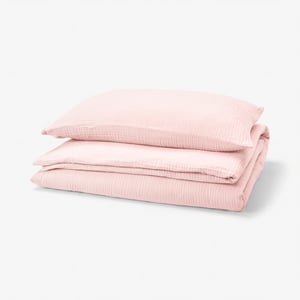 Stacked light pink SCHERSMIN cotton bedding set with textured design.