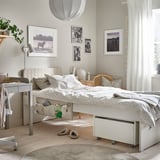 Kids room with white bed, horse decor, light wood floor. Bright, with pendant light, curtains, plant, bedside table, slippers, storage.