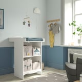 Modern nursery with SMÅGÖRA white changing table, blue walls, grey rug, hanging clothes, mobile, and chair.