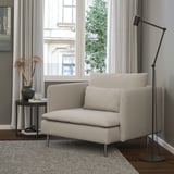 Modern living room: SÖDERHAMN armchair in beige, plush cushions, sleek design, beside small table with vase. Floor lamp stands tall nearby.