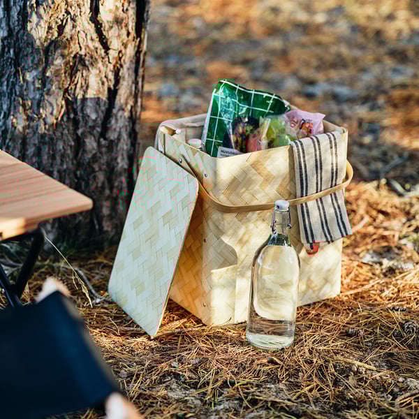 Wicker basket SOLUPPGÅNG with food and drink, placed by tree.