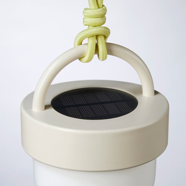 Modern solar-powered lamp. Bright white with green rope handle. Compact, sleek design.