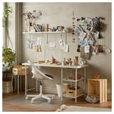 Creative workspace with SPÄND table, chair, books, vases on light grey wall.