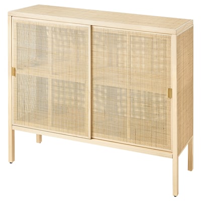 A STOCKHOLM 2025 beige cabinet with sliding doors made of natural rattan and solid pine, featuring elegant brass handles and a sleek design.