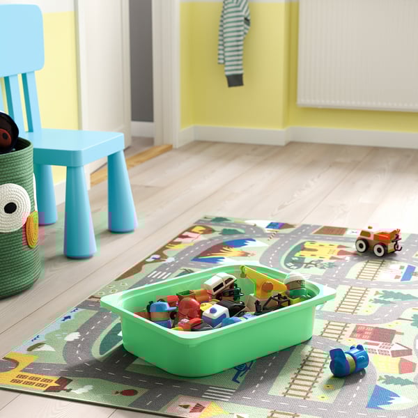 Kids playroom with colourful toys on a mat, blue chair, and green storage bin.