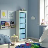Kids room with TROFAST light blue storage unit. Tall, narrow design, five drawers. Decorated with playful themes, space toys, books, and prints.