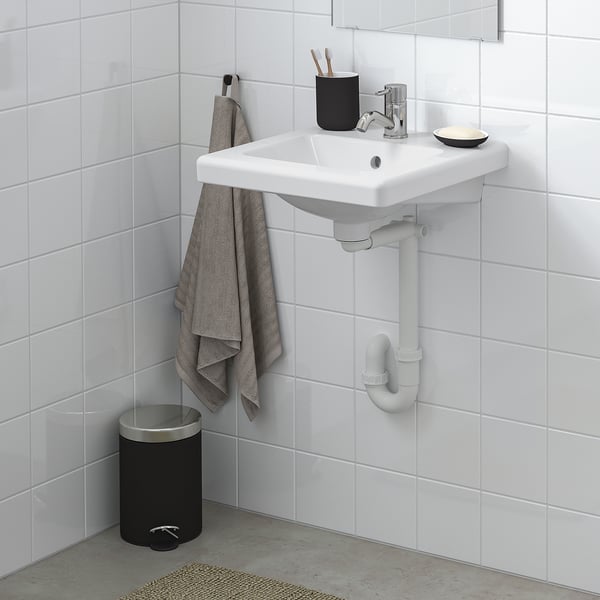 Modern bathroom with TVÄLLEN white sink, chrome tap, black accessories, grey towel, and white tiles.