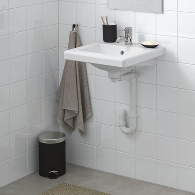 Modern bathroom with TVÄLLEN white sink, chrome tap, black accessories, grey towel, and white tiles.