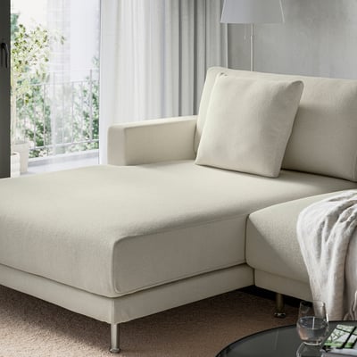 A modern, white UPPÅKRA sofa with deep cushions and a cosy design sits near a window, offering a comfortable spot for relaxation.