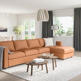 Modern living room with brown leather sectional, wooden coffee table, grey lamp, and large windows.
