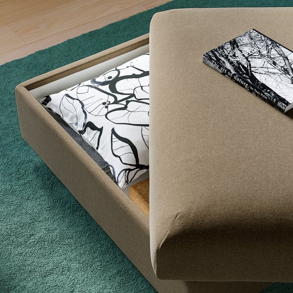 A beige VIMLE sofa with a patterned cushion and book on top. The cushion is removable and the sofa has storage.